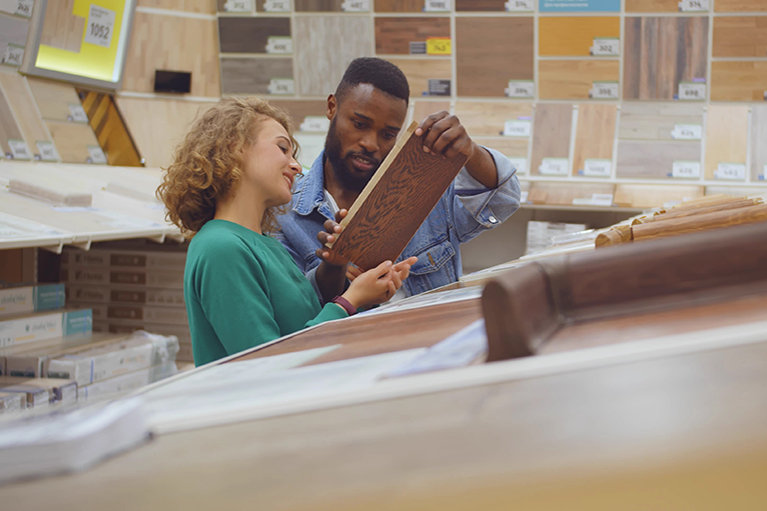 Diverse couple looking at parquet board for home flooring in store