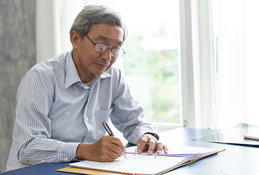 Asian smart business elder writing document report in the office